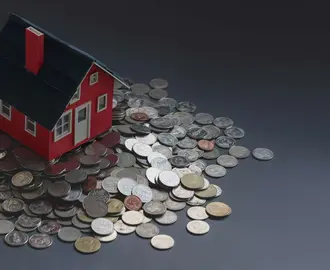 Toy house on pile of coins