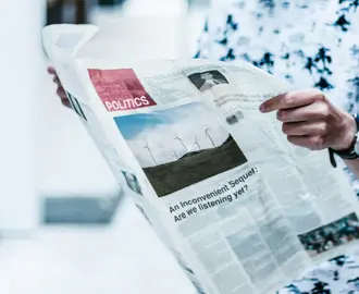 Person holding the politics section of a newspaper. Research finds variations of voters’ knowledge of political news across age, gender, race and socioeconomic status.