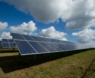 Solar panels in a field on a partly cloudy day