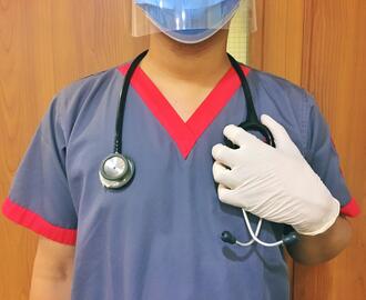 Nurse in face shield and mask with stethoscope draped over her shoulders