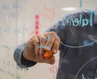 Person writing on glass wall 