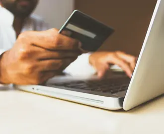 Man holding credit card over laptop