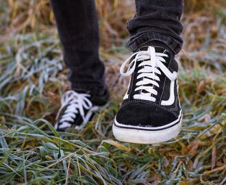 Close up of black sneakers on feet, standing on grass
