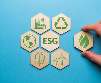 Hand pulling a hexagonal wooden tile away from a group of six other tiles with ESG in the middle