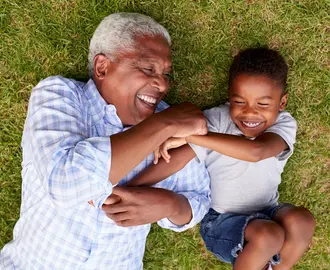 Grandfather and grandson play lying on grass, aerial view