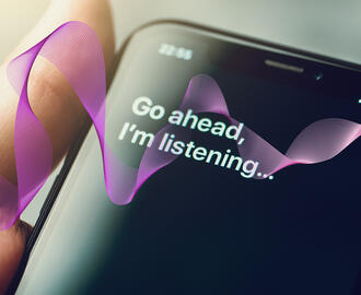 An iphone with Siri's words "Go ahead, I'm listening" on the screen. Graphic AI sound waves move through it. 