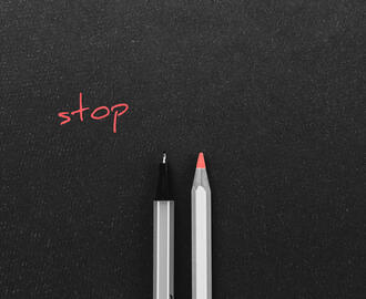 A pen and a colored pencil side by side with the word "stop" above