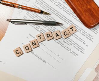 Image of a contract and office supplies, with the word "Contract" spelled out in Scrabble tiles