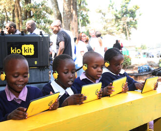 Children sitting in front of tablets smiling