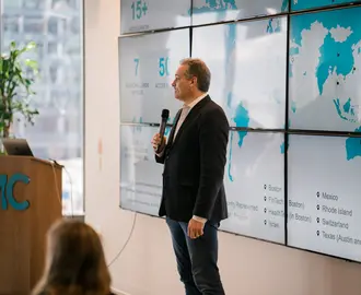 Phil Budden speaking in front of a world map on the wall