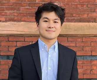 Headshot of MIT  Sloan PhD student Zach Tan, wearing a blazer jacket and blue shirt