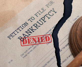 Petition to file for bankruptcy document torn in half with the stamp "denied" on it