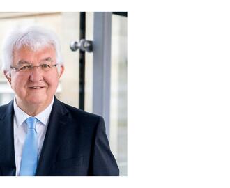 Robert Holzmann [older man with white hair, white skin and glasses wearing a dark suit with a light blue tie]