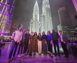 Two ASEAN Lab ASB student teams posing at night in front of a brightly lit tower in Kuala Lumpur
