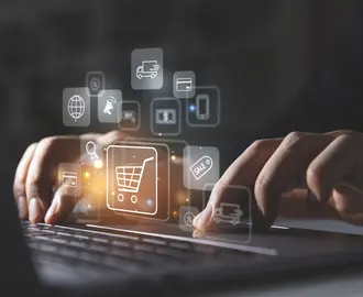 Young man using laptop with shopping cart icon