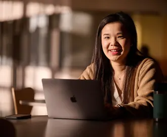 MBA Student Sharon Fan sits behind a laptop