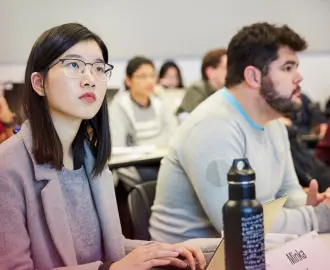 Students in the Masters of Finance program listen to a lecture in a classroom