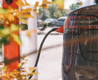 Image of the rear of an electric car that is being charged, with the charger visible