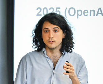 Mean holding remote speaks to audience in front of presentation