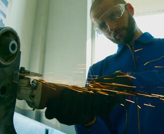 A worker in goggles is using a grinding machine