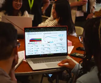 Undergraduate students explore the En-ROADS climate simulator on a laptop. 