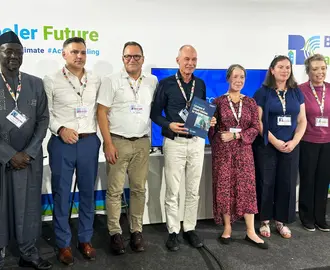 Event panelists, moderator, and organizers stand together.