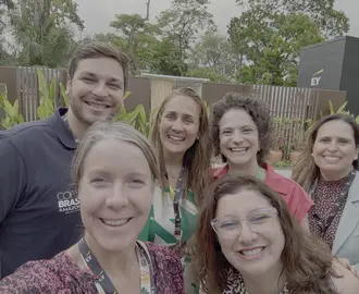 2 people smiling and 4 people smiling behind them posing for a selfie. 