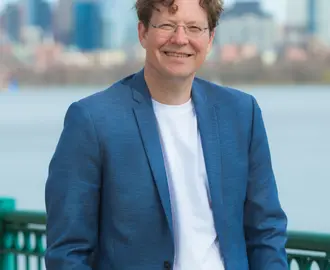 Headshot of a man outside in front of a river and skyline