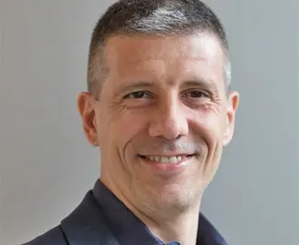 photo of a man with fair skin and gray hair wearing a navy blue shirt and jacket