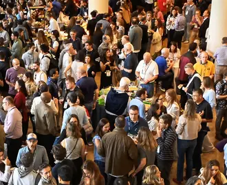 Large crowd gathers in a meeting space nearby banner that reads MIT Sloan Alumni Reunion