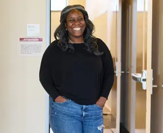 Alecia Asiamigbe walks through the halls of MIT Sloan, smiling at the camera