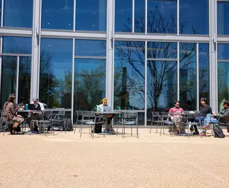 Students sitting at tables in front of the Memorial Drive entrance of E62