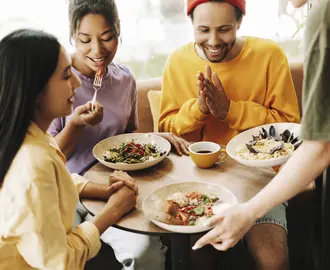 Waitress bringing food to a group of three friends in a restaurant.