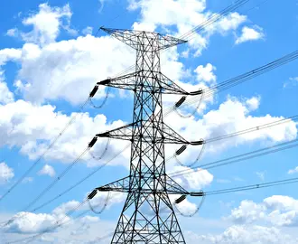 Electricity pylon with high voltage lines set against a vibrant blue sky with clouds.