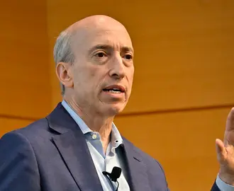 Man wearing business casual suit speaks before audience.