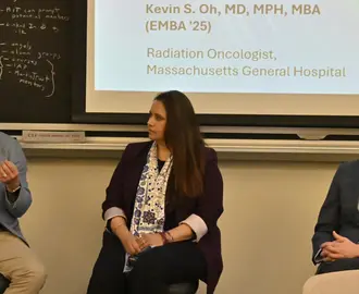 Three people on a panel listen to a fourth panel member speak.