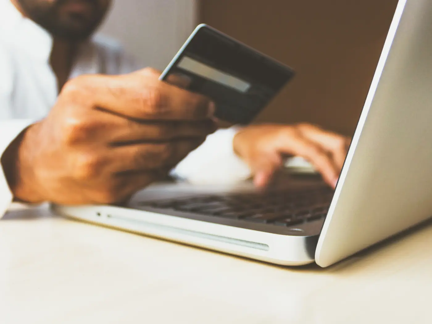 Man holding credit card over laptop