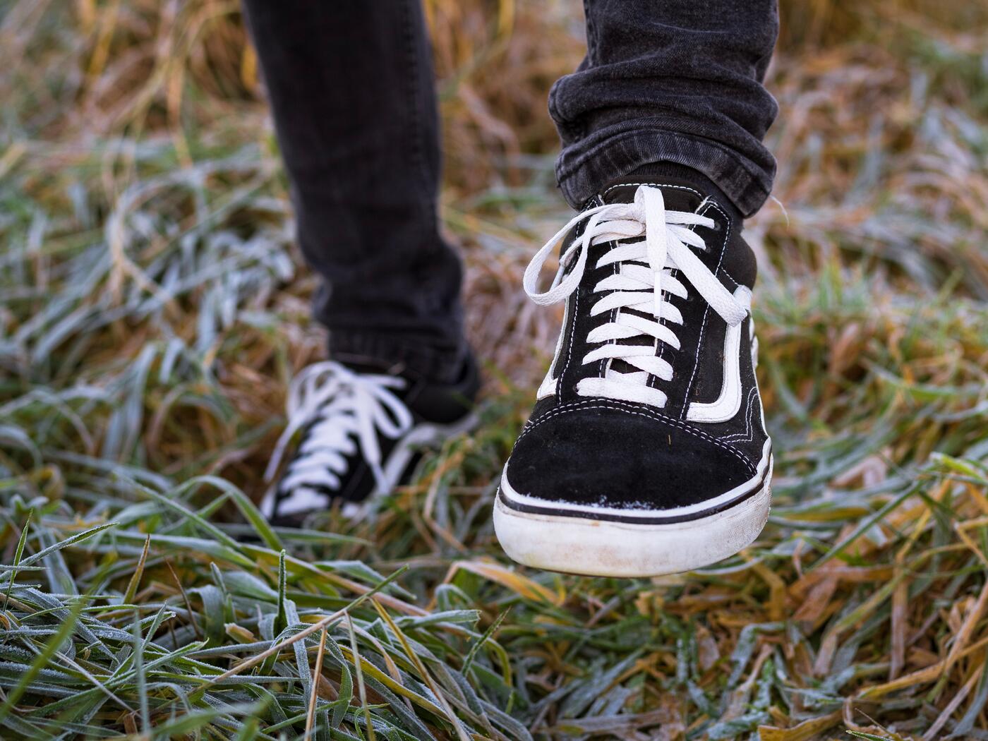 Close up of black sneakers on feet, standing on grass