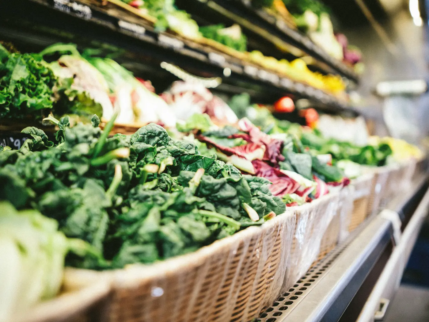 Market shelf with baskets of leafy produce