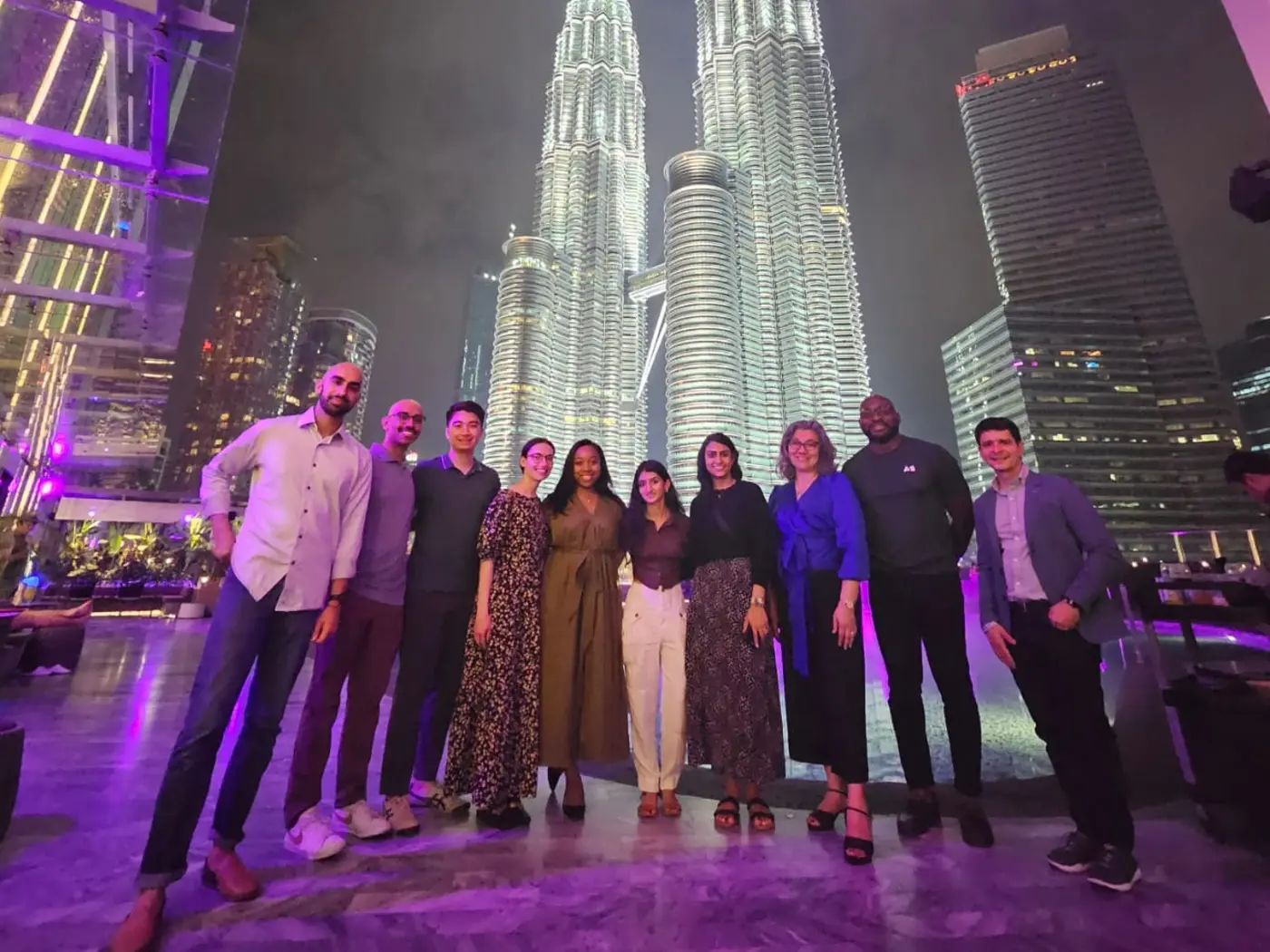 Two ASEAN Lab ASB student teams posing at night in front of a brightly lit tower in Kuala Lumpur