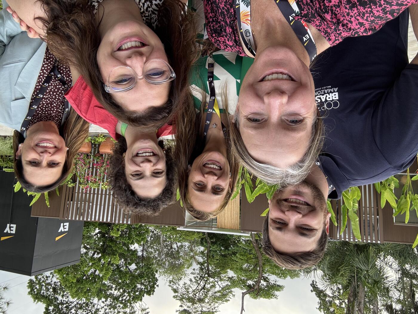 Group selfie of 6 smiling people outside.