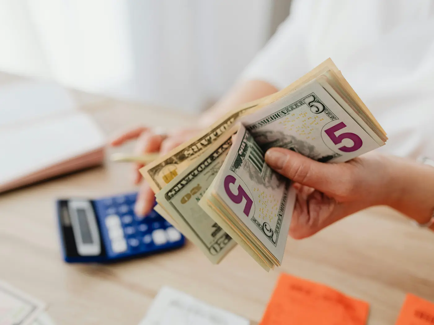 person holds cash and uses a calculator