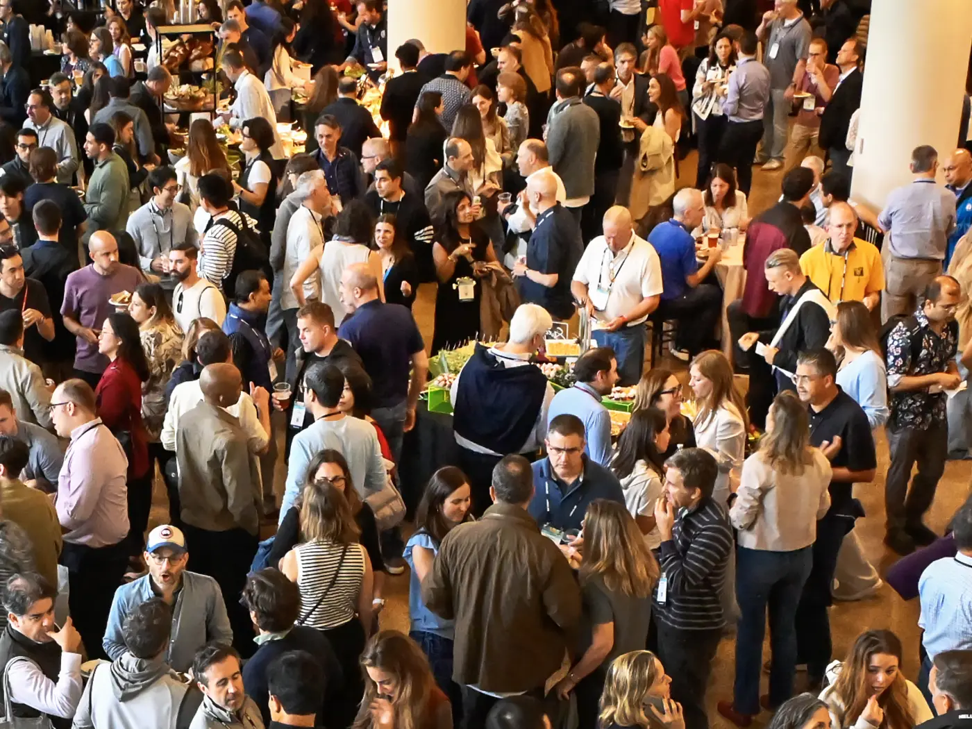 Large crowd gathers in a meeting space nearby banner that reads MIT Sloan Alumni Reunion
