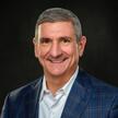 Man with short gray hair smiling at the camera.