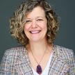 A woman with short curly blond hair smiling