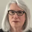 Woman with shoulder length silver hair and glasses.