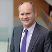 photo of a man wearing a gray suit, a purple dotted tie, and a white shirt