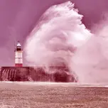 Huge waves crash over harbor sea wall and lighthouse
