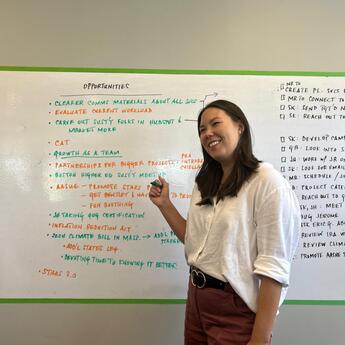 Grace Bambushew, 2024 Intern, in front of a white board
