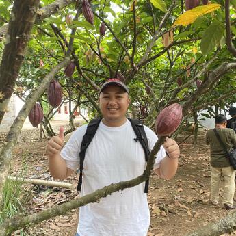 Summer intern next to a cocoa tree